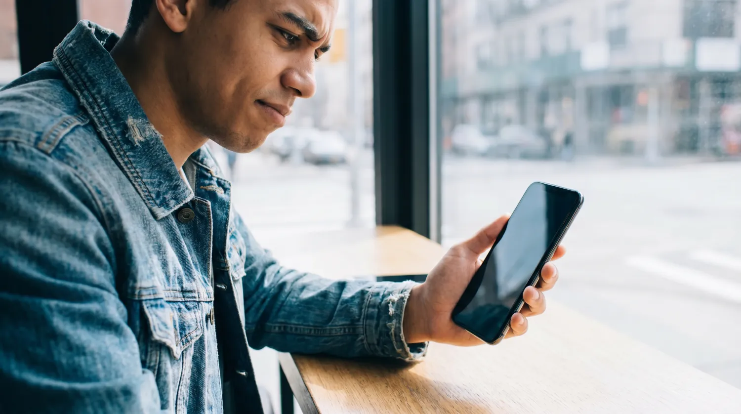 Personne dubitative regardant un téléphone à l'écran éteint